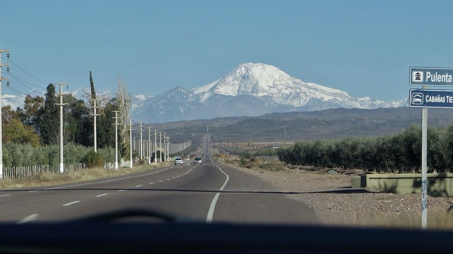 Road by mountains seen through car windshield