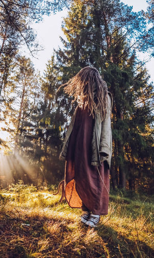 Full length of woman with dreadlocks standing in forest