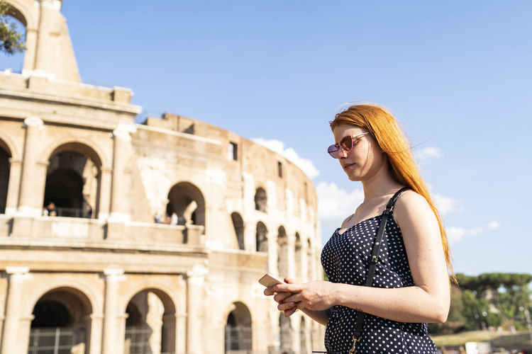 Trendy tourist with smartphone outside ancient attraction
