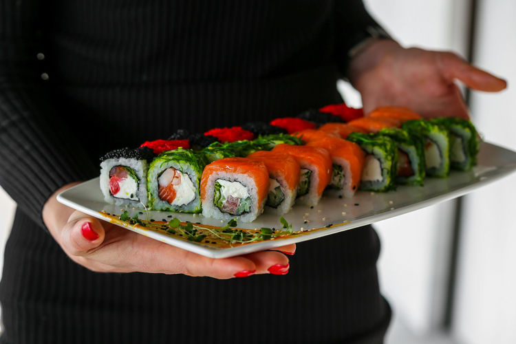 Midsection of woman holding sushi in plate