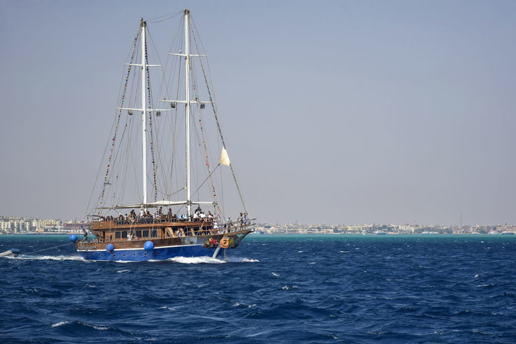 People relax on stylized sailing ship on sunny day. vacation on red sea, holidays, adventure, travel