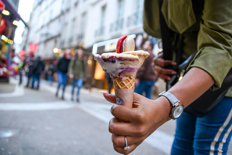 Midsection of person holding ice cream on street