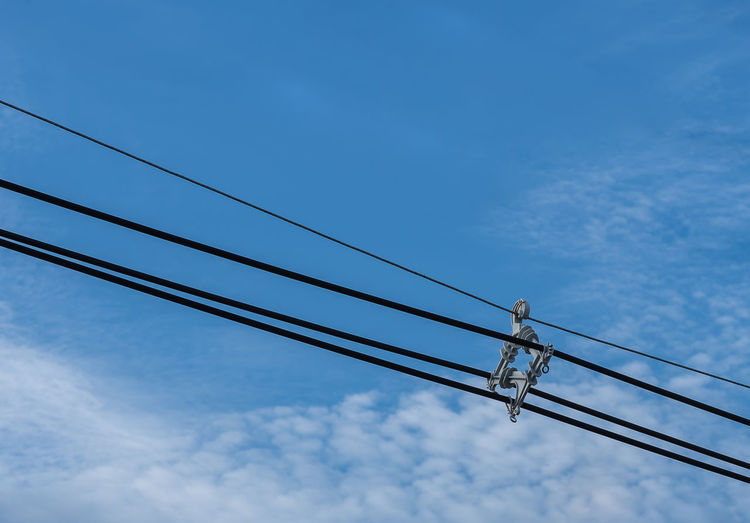Low angle view of electricity cable against blue sky