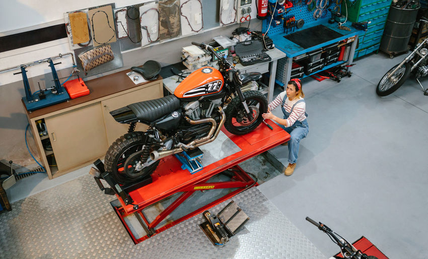 Mechanic woman reviewing custom motorcycle over platform