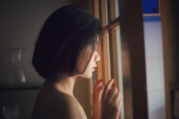 Side view of young woman looking down from window