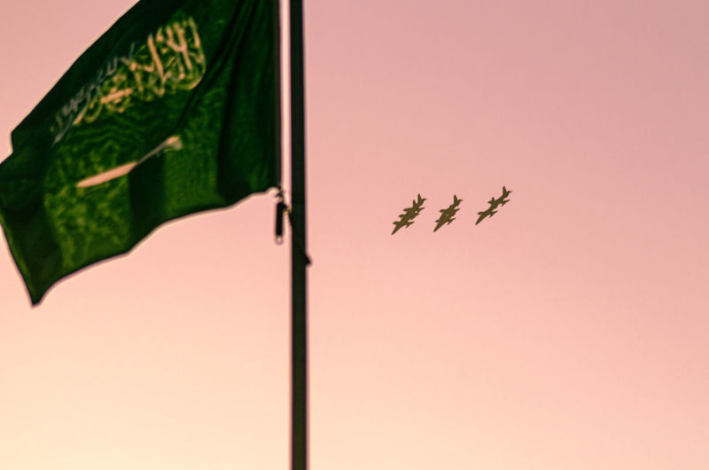 Low angle view of airplanes in sky with flag