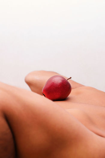 Close-up of hand on apple against white background
