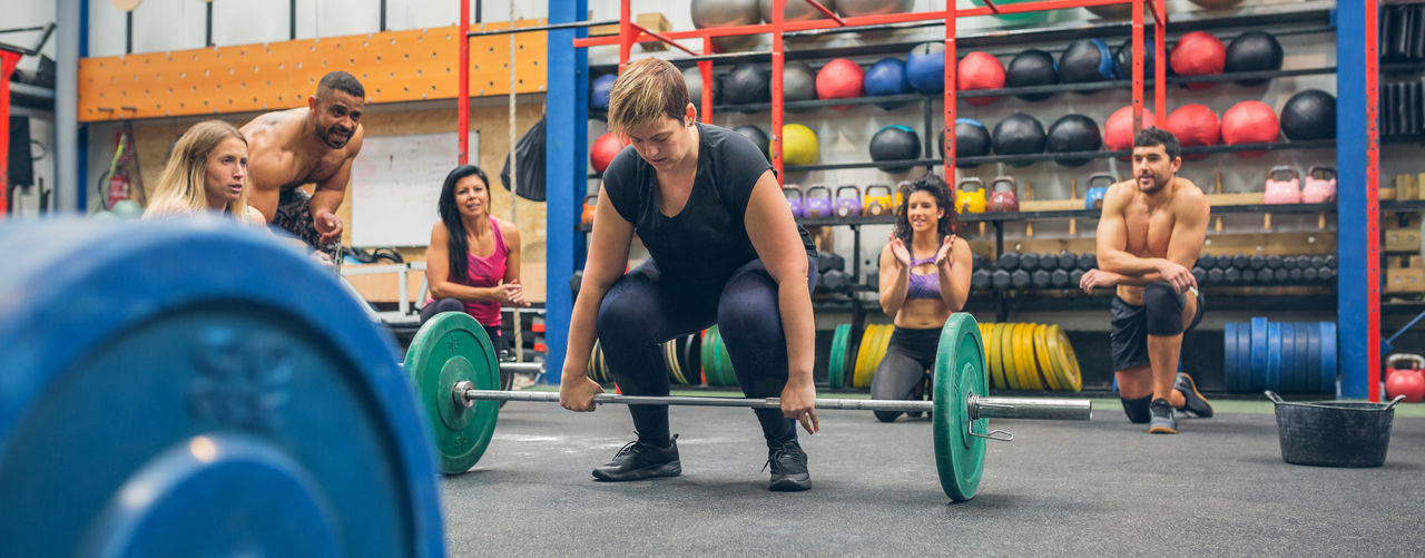 Woman ready to do weightlifting while her gym mates cheering her on