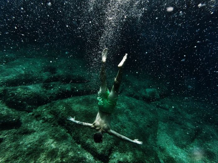 Rear view of shirtless man swimming in sea