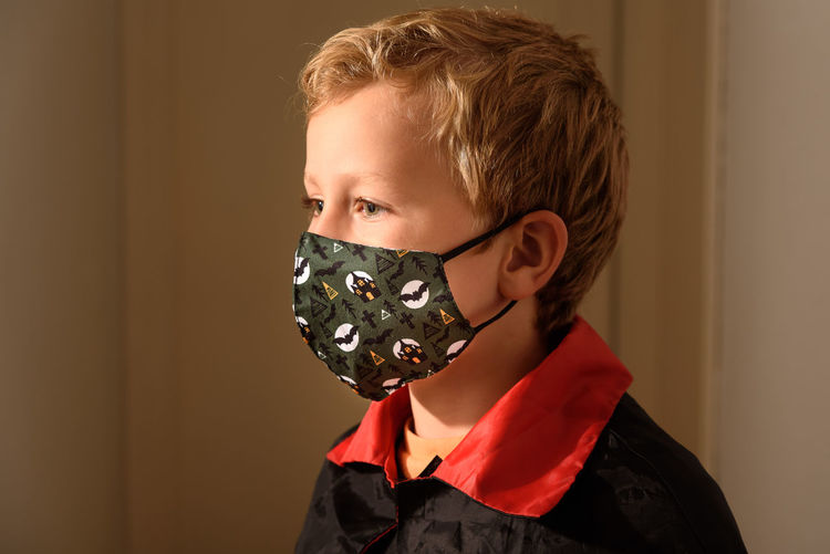 Close-up of boy wearing mask sitting at home