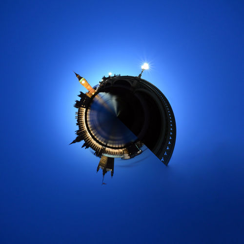 Little planet effect of illuminated cityscape against clear blue sky