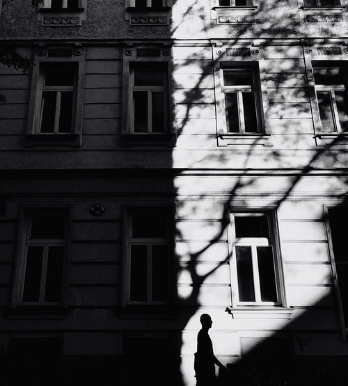 Low angle view of silhouette woman standing against building