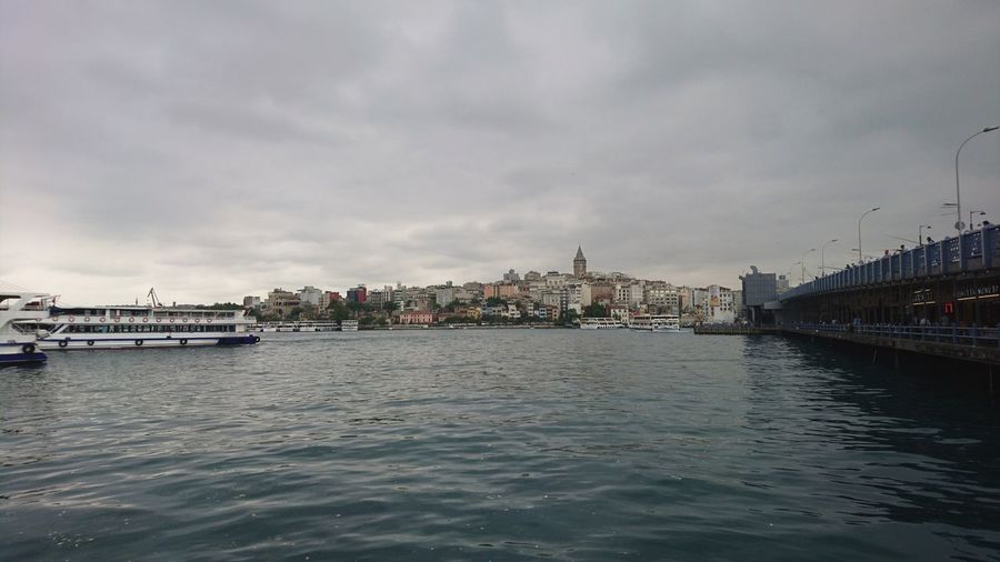 Boats in river against sky in city