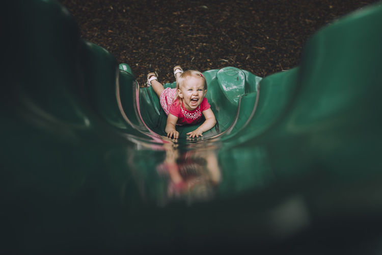 High angle portrait of happy baby girl playing on slide at playground