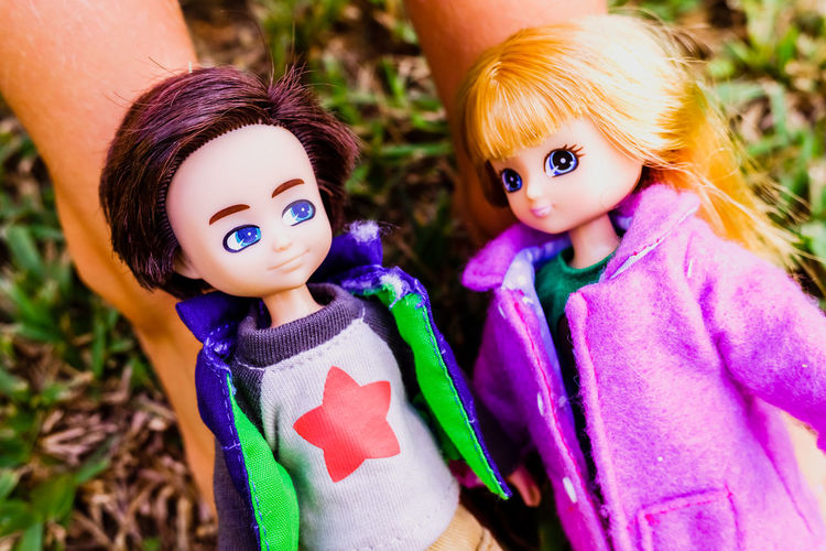 Close-up of hand holding dolls on grass