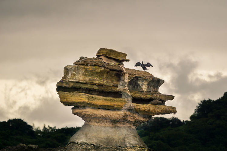 Low angle view of stacked rocks against cloudy sky