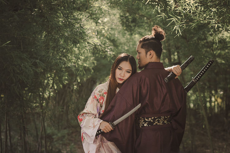 Couple with sword standing in forest
