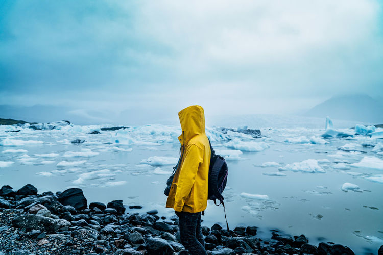Woman standing on snow covered shore against sky