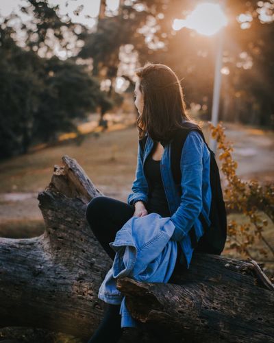 Side view of woman sitting on wood