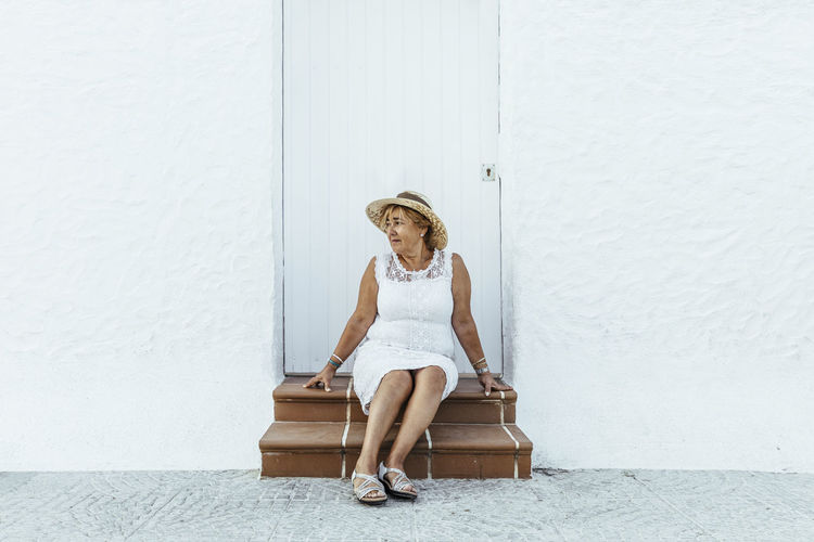 Senior tourist sitting on stoop in a village, el roc de sant gaieta, spain