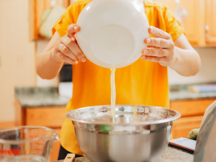 Midsection of woman pouring butter in pan