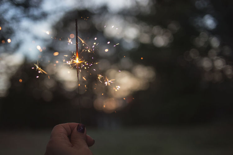 Close-up of hand holding sparkler at night