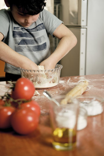 Child preparing pizza dough to make at home