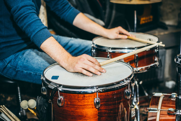 Midsection of man playing drums at music concert