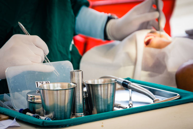 Close-up of dental tools with doctor operating patient in office