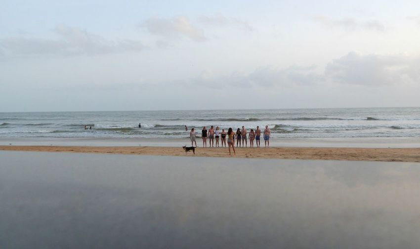 Group of people standing at beach against sky