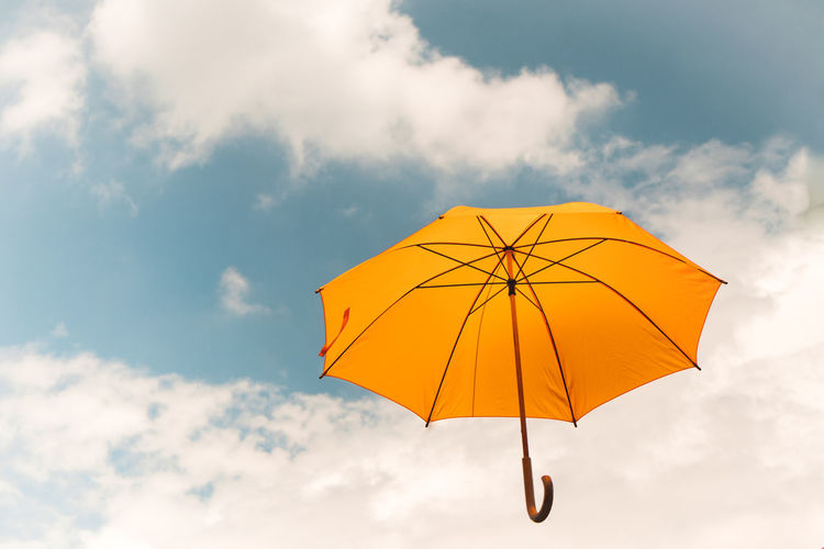 Low angle view of yellow umbrella against sky