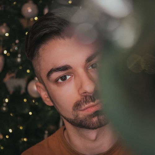 Portrait of a young man behind christmas decorations.