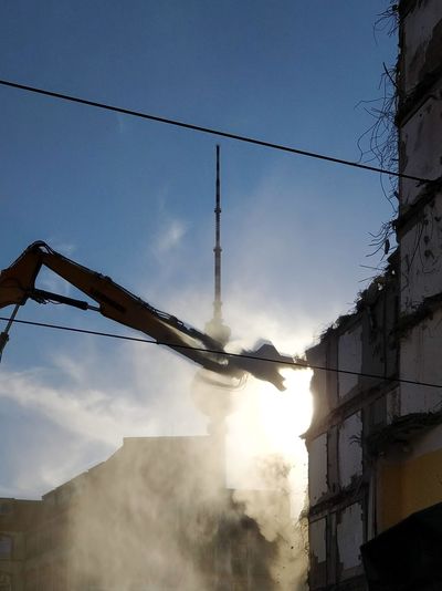 Low angle view of crane at construction site against blue sky