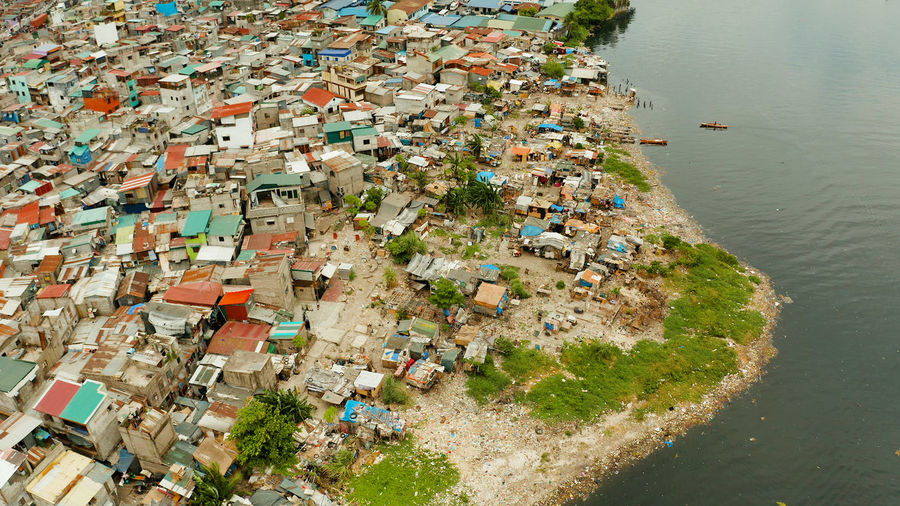Slums in manila on the bank of a river polluted with garbage, aerial view.