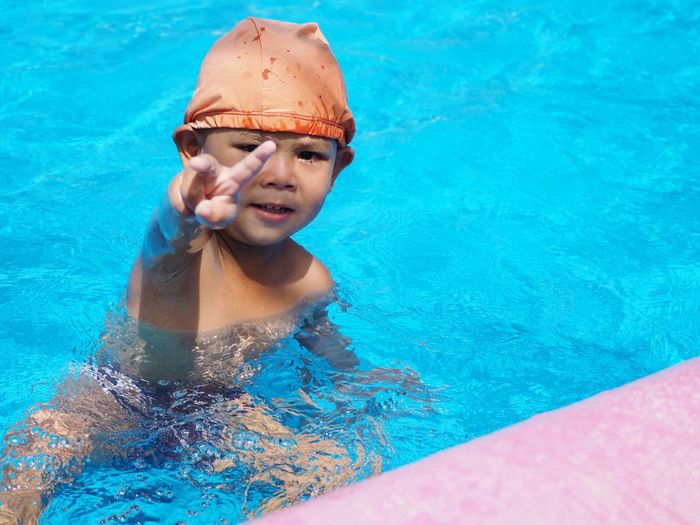 Portrait of boy gesturing while swimming in pool