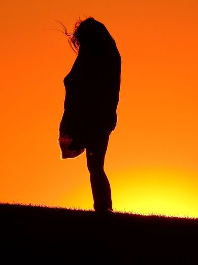 Silhouette person on field during sunset