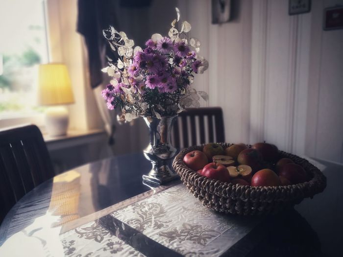 Flower vase on table at home. apples and bears in basket. autumn. 
