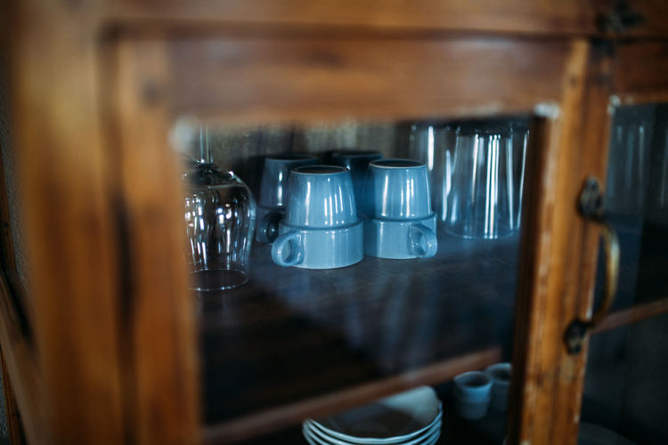 Close-up of glasses and cups in cupboard.