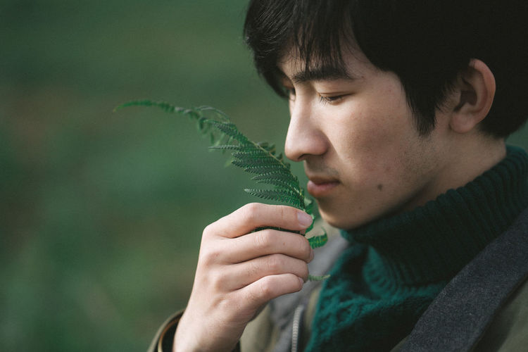 Close-up of man smelling leaves