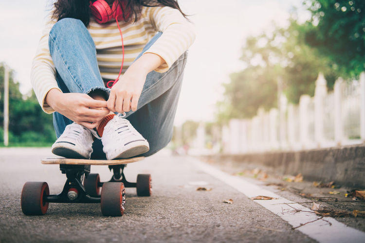Low section of woman sitting on skateboard