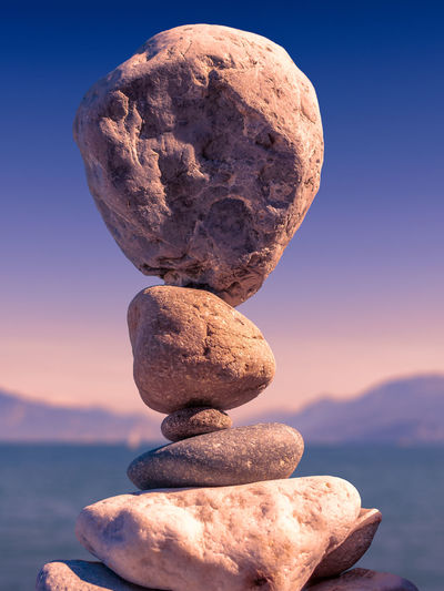 Stack of stones on rock against sky during sunset