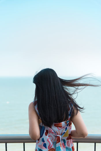 Rear view of woman against sea against clear sky