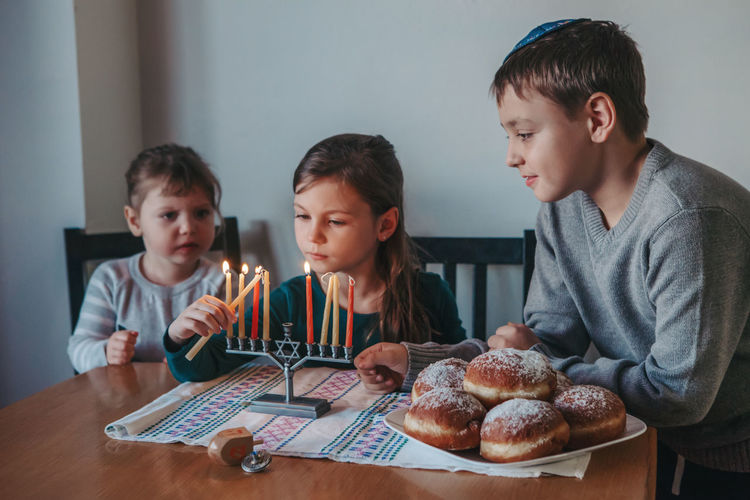 Cute kids igniting candles at home
