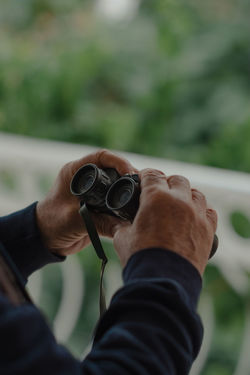 Hands of a man holding binoculars. close-up image.