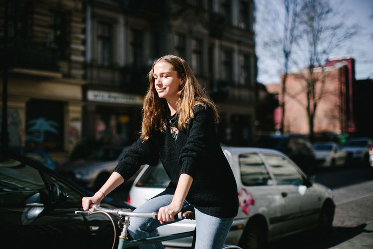 Young woman smiling while holding cars on street in city