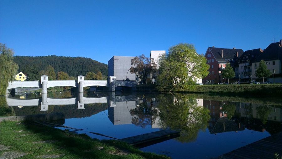 Reflection of building in lake against clear blue sky