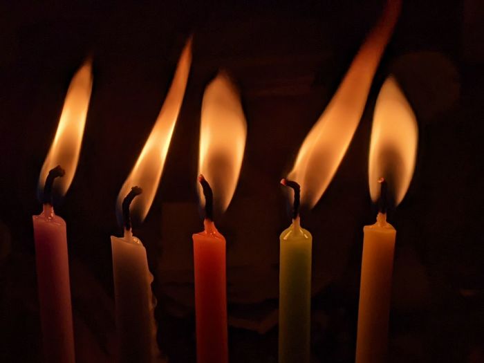 Close up of five hanukkah candles burning against a dark background