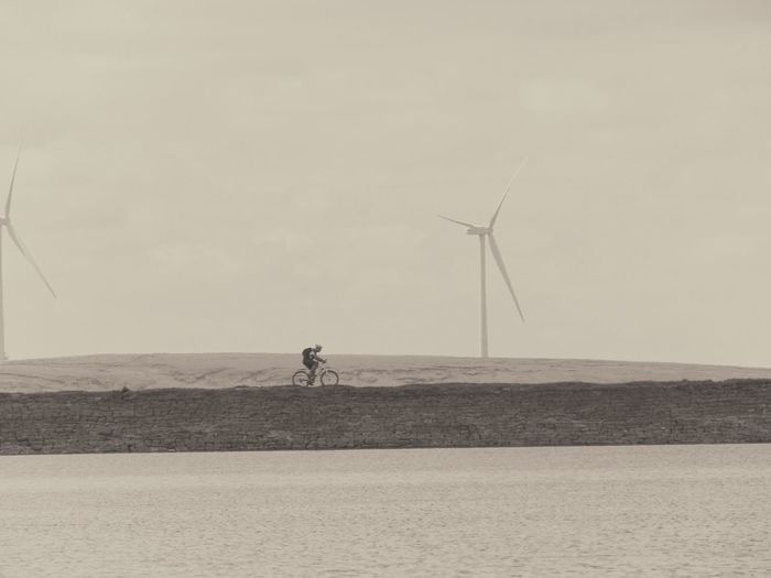 Mid distance shot of wind turbines in sea against clear sky