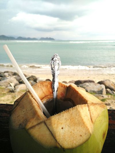 Close-up of breakfast on beach against sky