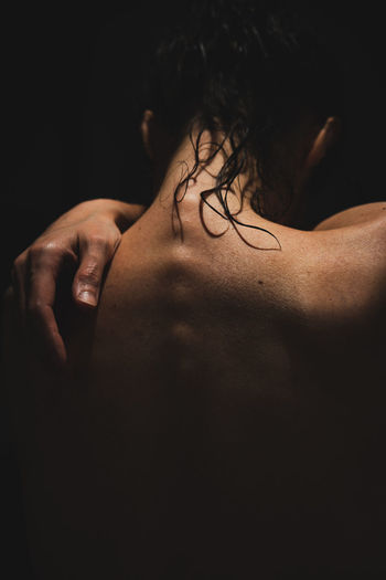 Rear view of shirtless woman against black background